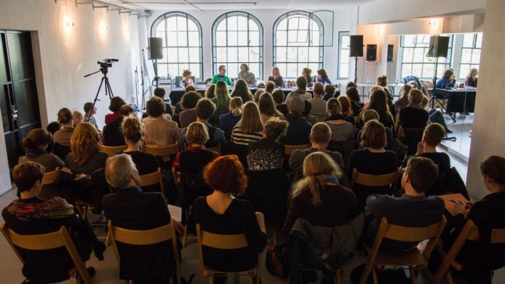 Viele Menschen hören ein paar sprechenden Menschen zu.