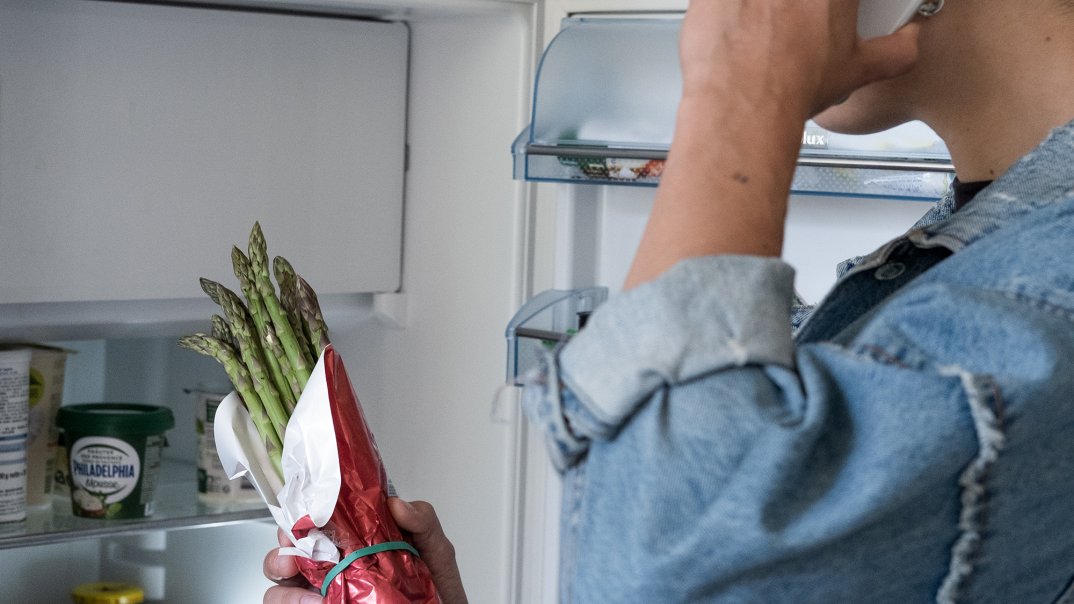 Person mit Telefon am Kühlschrank