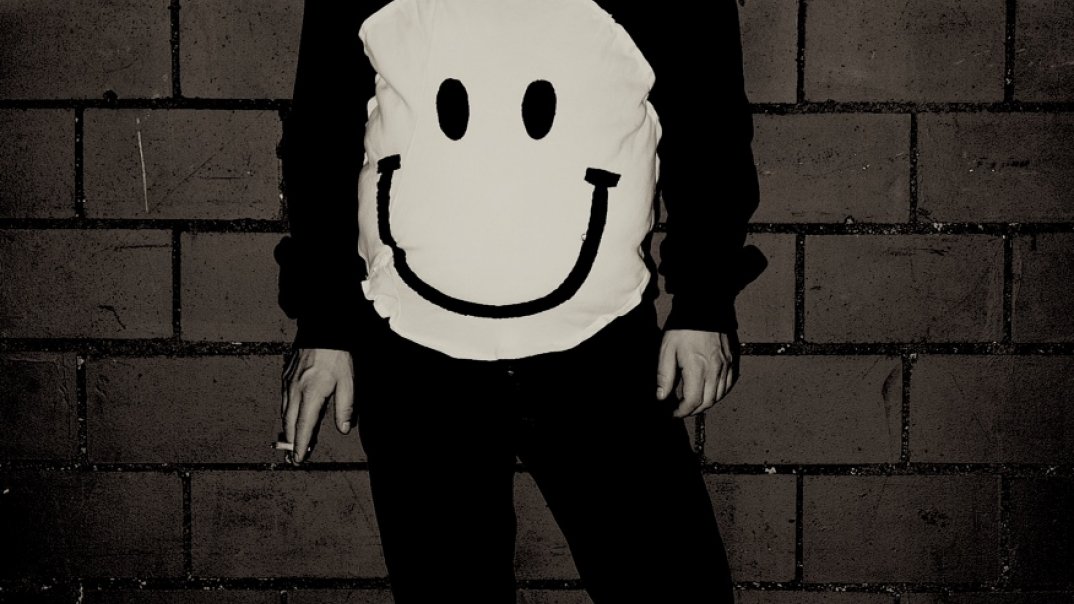 Ein  Mann trägt einen Pulli mit Smiley-Sujet