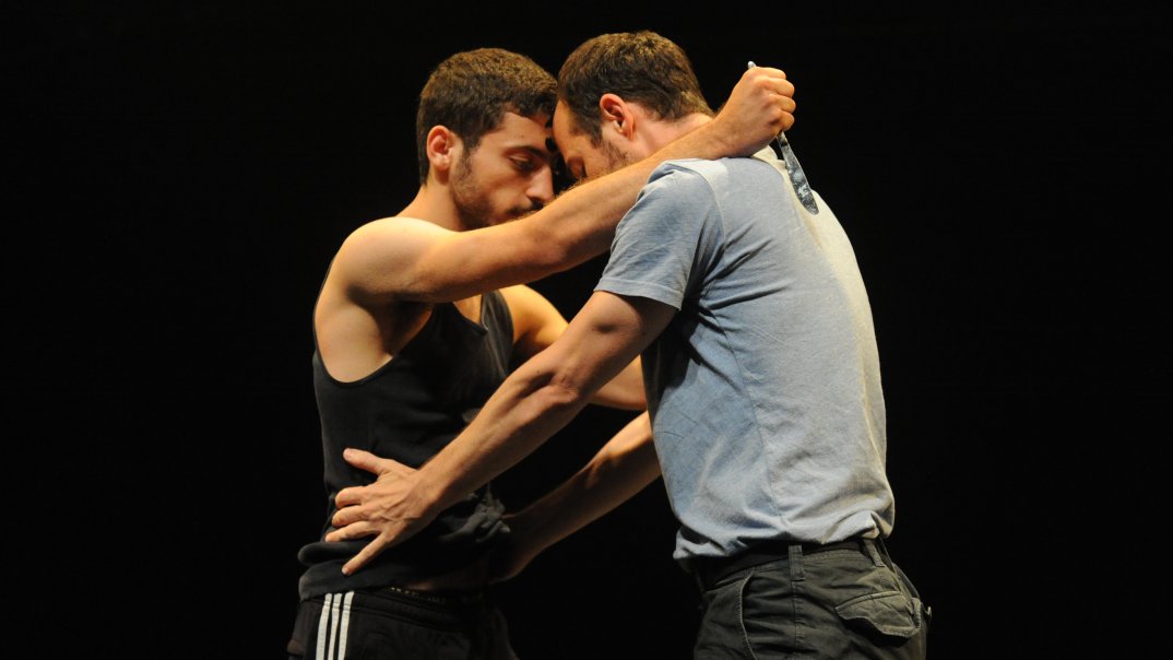 Zwei tanzende Männer halten sich an den Armen. 