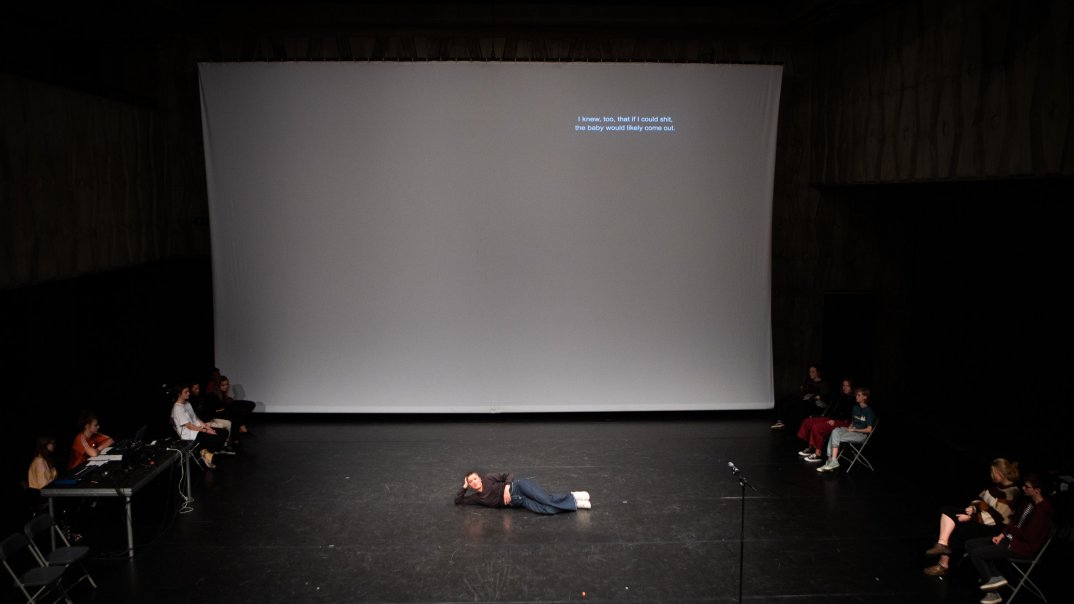 Eine Person legte sich vor einer großen Leinwand auf den Boden