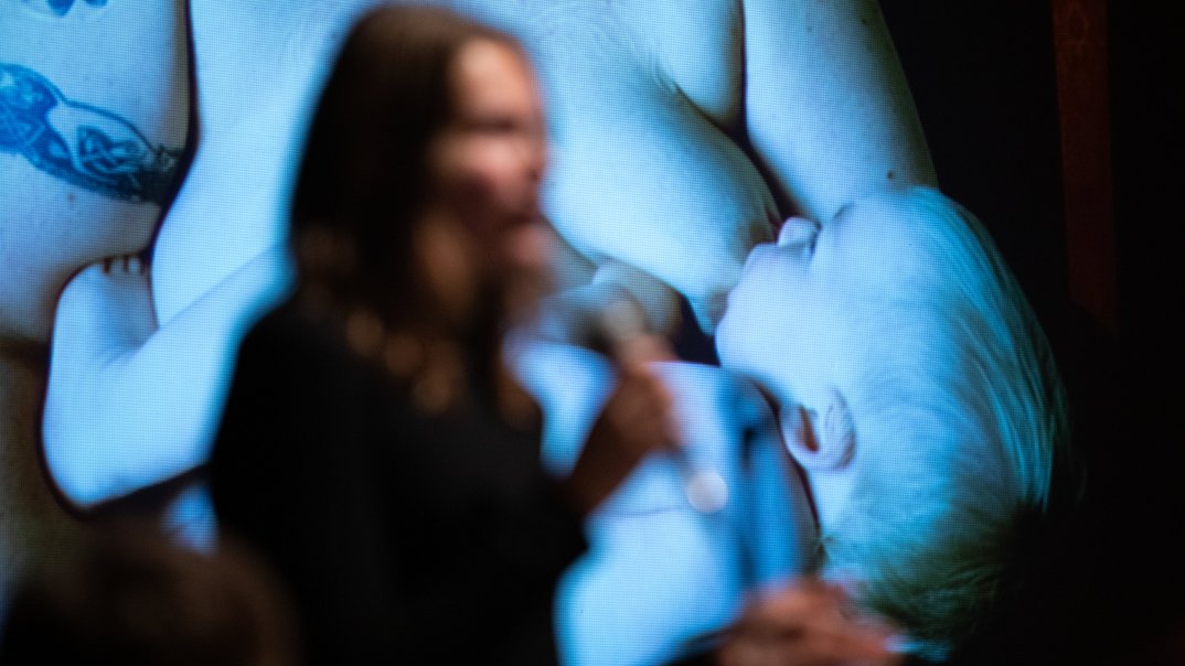 eine Frau, die vor einem Bildschirm mit einem Babyfoto auf dem Bildschirm steht