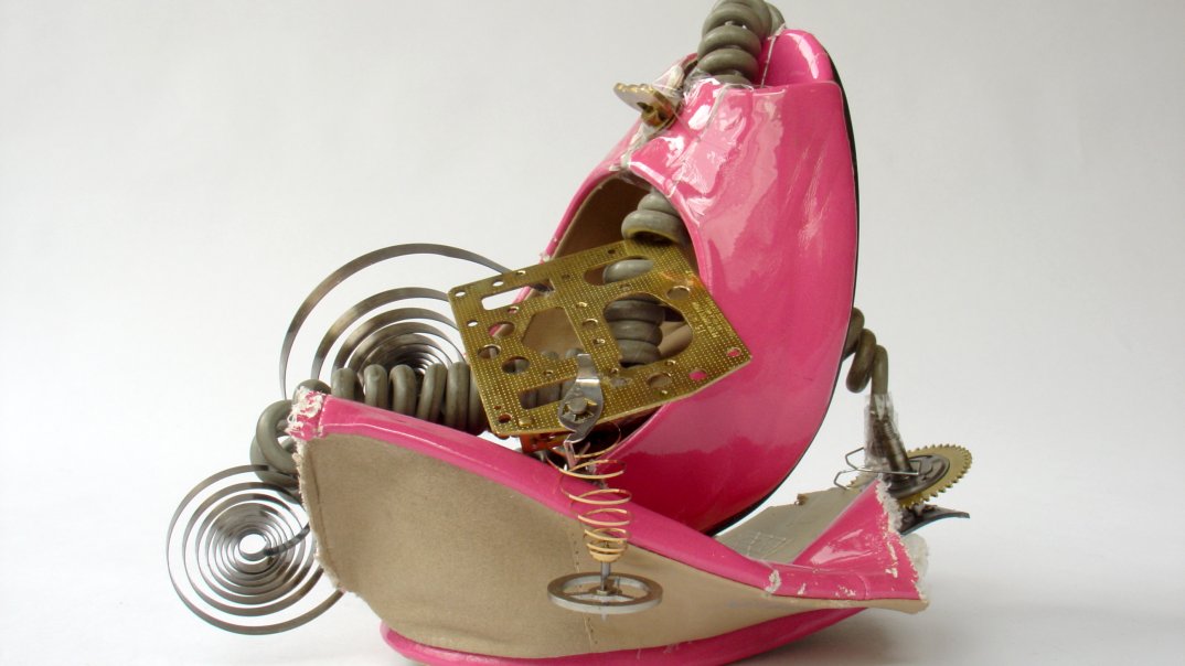 Eine pinke High Heels wird zu einem Kunstwerk verarbeitet und wird mit Spiralkabeln und einen kleinen Metallstück verseht.